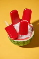 Watermelon popsicle sticks over yellow background, summer mood