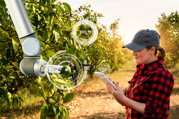 Woman farmer controls robotic arm with a tablet. Smart farming and digital transformation in...