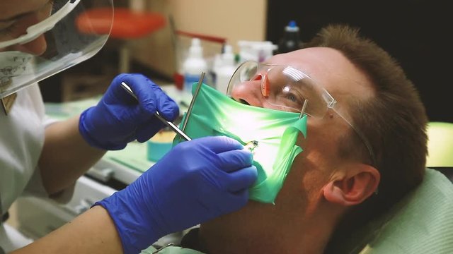 The patient treats teeth in a dental clinic. Filling of root canals of teeth-gutta-percha is used.