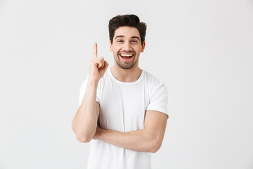 Excited young man posing isolated over white wall background pointing.