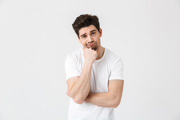 Fototapeta na wymiar Tired bored young man posing isolated over white wall background.