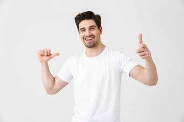 Excited happy young man posing isolated over white wall background pointing to himself and you.