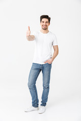 Excited young man posing isolated over white wall background showing thumbs up gesture.