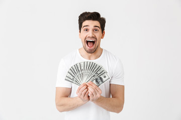 Shocked excited happy young man posing isolated over white wall background holding money.