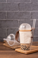 Takeout with disposable item concept popular Taiwan drink bubble milk tea with plastic cup and straw on wooden table background, close up, copy space