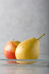 Ripe juicy pear on the table in a glass plate.