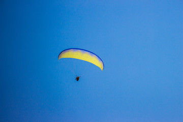 Man flies on a parachute against the sky.