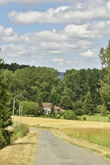 Petite route secondaire de campagne et l'une des fermes à la lisière de la forêt près du bourg de Champagne au Périgord Vert