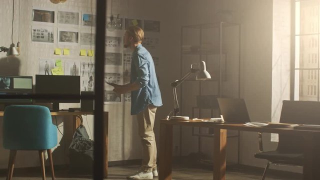 Young Creative Designer Looks at the Storyboard Sketches Covering his Wall, He Chooses Between Concept Drawings, Wondering How to Proceed with this Important Story for His Video Gaming Project