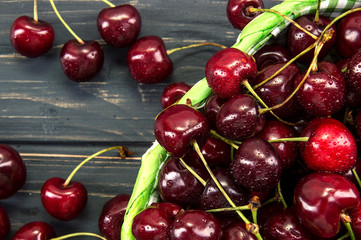 Top view, flat lay. Close up, macro. Ripe maroon cherries in a green wicker basket.