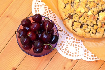 Crumble vegan cake with integral flavour on pergament paper and plate full of ripe cherries