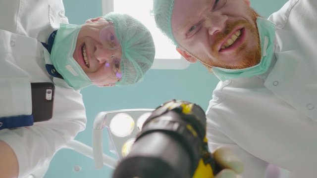 Bottom view portrait of two male crazy dentists with drill. Fun joke concept