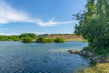 Sunny summer day at an abandoned quarry for the extraction of stone.