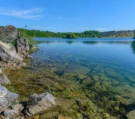 Sunny summer day at an abandoned quarry for the extraction of stone.