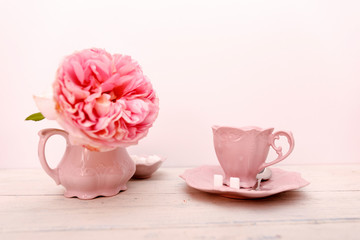 Big roses and empty coffee cup on a white wooden background.