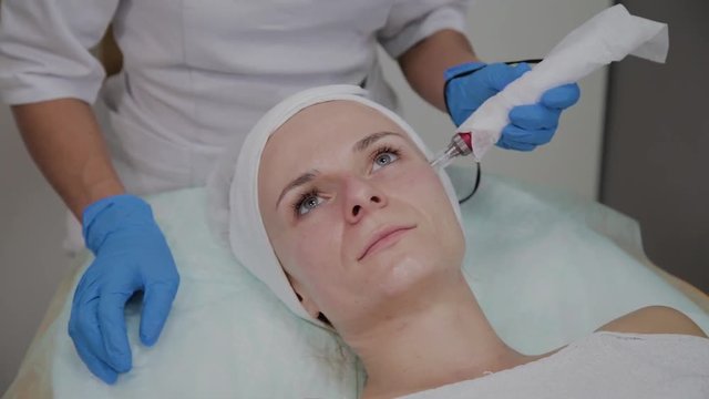 Professional cosmetologist performs DermaPen procedure in a cosmetology clinic.