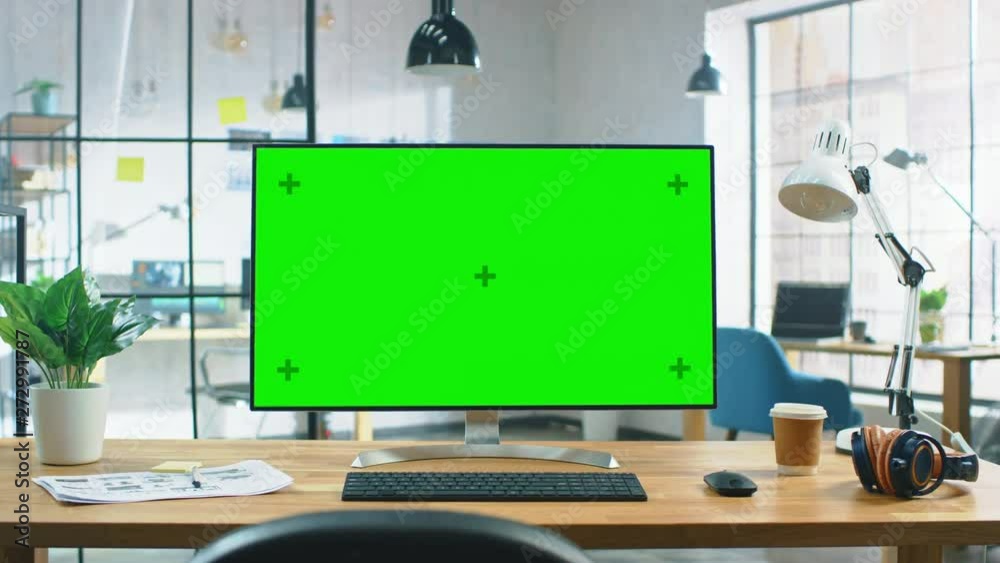 Poster wide green mock-up screen desktop computer standing on the desk in the modern creative office. in th