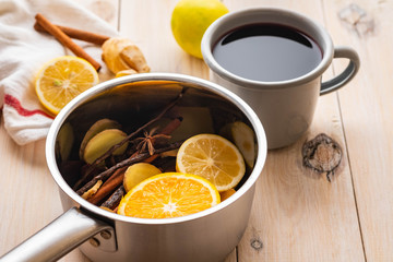 Mulled wine hot drink with citrus, apple and spices in aluminum casserole and Fir branch on background.