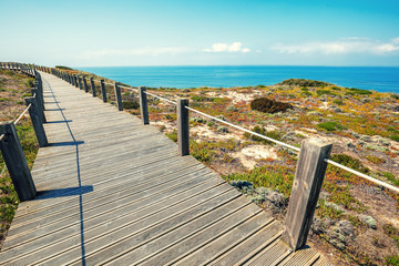 The wooden stairway at the rocky seashore on a sunny day. Polvoeira the beach. Pataias, Portugal, Europe