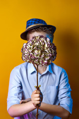 man in a hat holding a bouquet in front of his face on a bright colored background