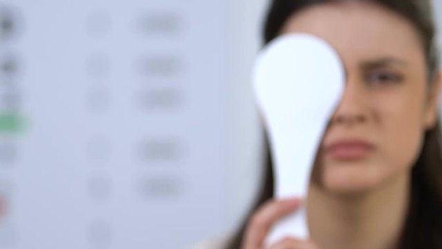 Girl closing one eye, focusing vision on doctor appointment, refocus problem