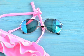 Colorful aviator sunglasses and neon trendy bikini with selective focus on wooden textured...