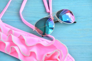 Colorful aviator sunglasses and neon trendy bikini with selective focus on wooden textured...