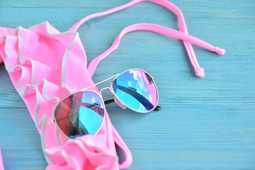 Colorful aviator sunglasses and neon trendy bikini with selective focus on wooden textured...