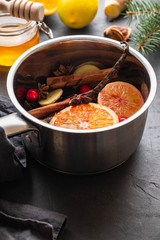 Mulled wine hot drink with citrus, apple and spices in aluminum casserole and Fir branch on background.