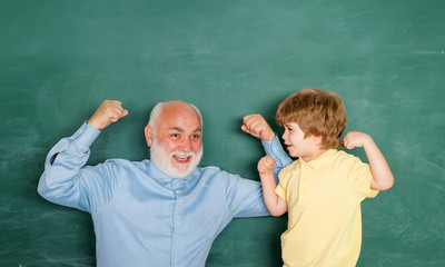 Teacher helping his teen pupil on education class. Concept of education and teaching. Portrait of confident old male teacher. Happy Pupil with over blackboard background.