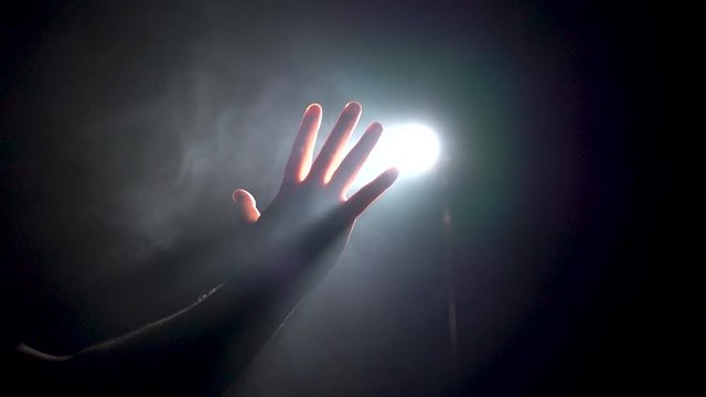 man hand touches the light in the dark