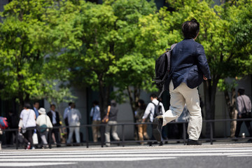 走って横断歩道を渡るビジネスマンの後ろ姿