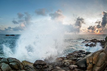 The waves break on the rocks at sunset.