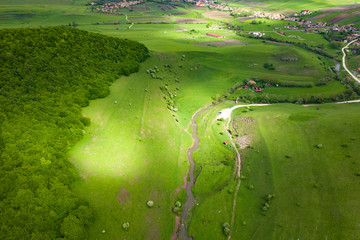 Drone view of green meadows and villages in Transylvania.