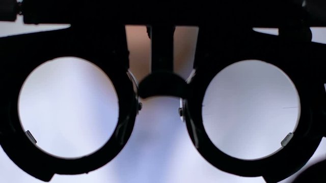 Patient looking through phoropter on vision examination, ophthalmological clinic