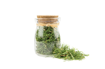 Pile of dried natural herbal medicine called Equisetum arvense the field horsetail or common horsetail isolated on white next to filled glass jar.