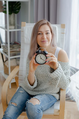 Blonde young woman holding a black clock