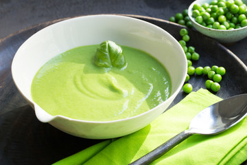 Vegane Erbsensuppe mit Basilikum in Suppenschüssel mit Löffel serviert