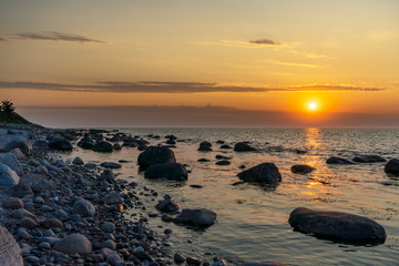 Fototapeta na wymiar Sunset at a stony beach with cloudy horizon