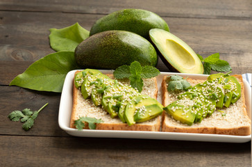fresh avocado with whole wheat bread and sesame in dish on wood background
