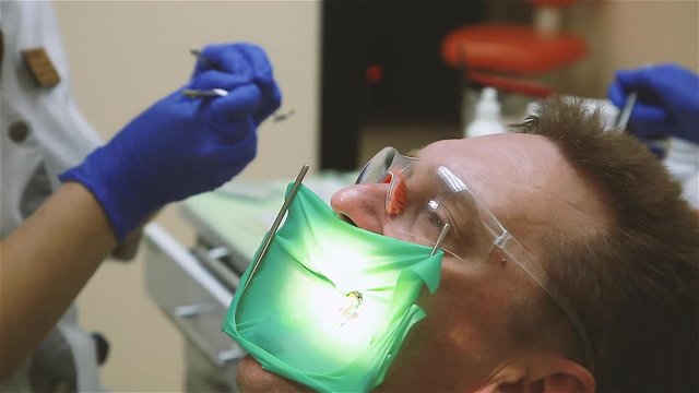 The patient treats teeth in a dental clinic. Filling of root canals of teeth-gutta-percha is used.