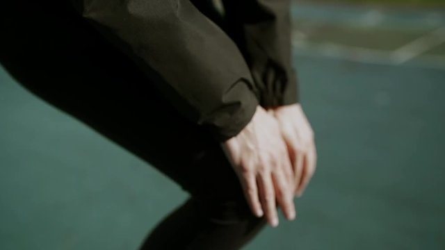 Fitness runner body closeup doing warm-up routine before running, stretching leg muscles with standing single knee to chest stretch. Female athlete preparing legs for cardio workout.