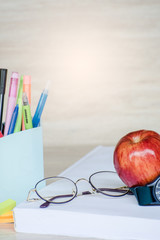 Abstract education, red apples, multicolored pens and white books with wooden backgrounds