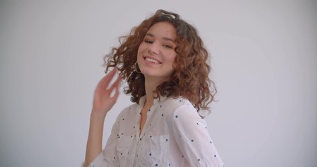 Closeup shoot of young stylish long haired curly caucasian female tossing hair smiling seductively looking at camera with background isolated on white