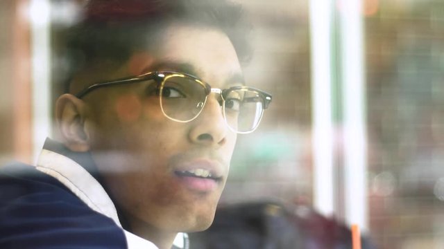 Chicago, IL/United States-June 12th 2019:  Young attractive Middle eastern male model winks at the camera from behind the window glass at a local Chicago shop.  the student wears trendy sunglasses 