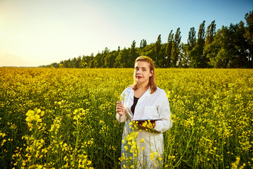 Agronomist woman or farmer examine blossoming rape (canola) field using tablet
