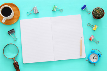 Open notebook with empty pages and other office supplies over blue office desk table. Top view