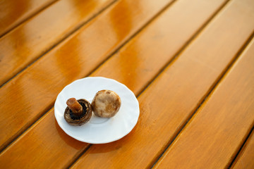 Grilled champignons on a white plate on a wooden table. Healthy food. Close up.