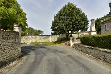 Tournant d'une route de campagne entre les vieux murs en pierre pr&egrave;s du monument de comm&eacute;moration de Vendoire au P&eacute;rigord Vert