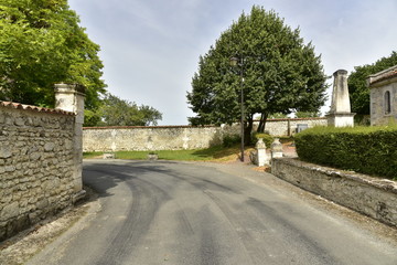 Tournant d'une route de campagne entre les vieux murs en pierre près du monument de commémoration de Vendoire au Périgord Vert